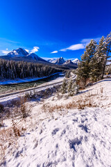 A snowy mountain range is in the background of a train track