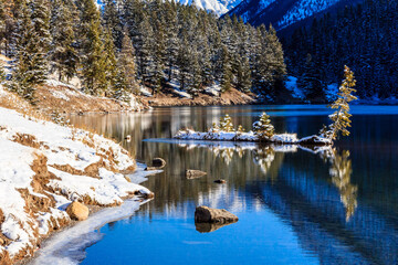 A snowy landscape with a body of water and trees