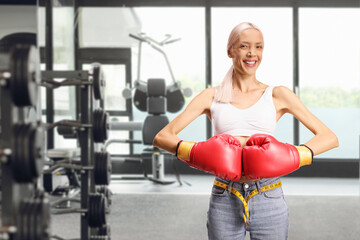 Fototapeta premium Slim woman with boxing gloves smiling and posing