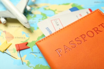 Passport with tickets and plane model on world map, closeup