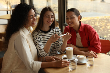 Woman taking picture of coffee drinks during meeting with her friends in cafe