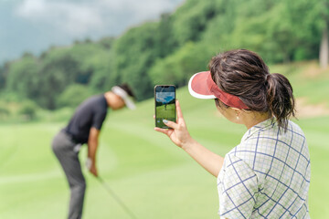 ゴルフ場でスマホを使って動画を撮ってスイングの確認をするゴルファー
