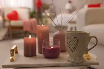 Burning candles and cup of hot drink on table in room