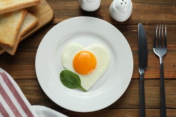 Romantic breakfast with heart shaped fried egg served on wooden table, flat lay