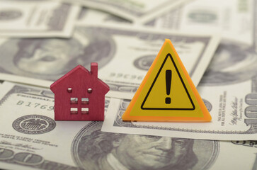 the house and the warning sign serves as a reminder of the financial responsibilities and potential pitfalls of owning a property.