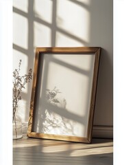 Empty wooden picture frame leaning against white wall in sunlit room