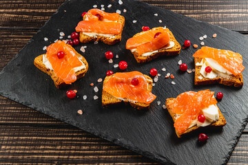 Toasts with butter, mozzarella and salmon on a wooden table for breakfast