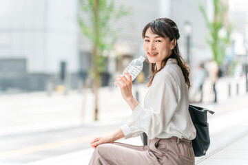 Fototapeta premium 外出中にペットボトルの水・飲み物を飲むビジネスウーマン 