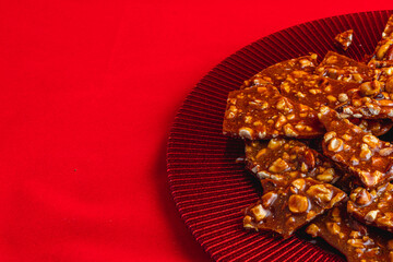 Homemade sweet gozinak with various nuts on a red plate, Christmas concept
