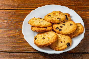 Delicious Christmas cookies with raisins on a white plate on a wooden table
