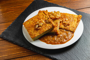 Oven-baked potato pancakes with mushroom sauce and onions on a stone board