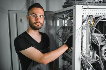 Repairman is busy and working with internet equipment and wires in server room