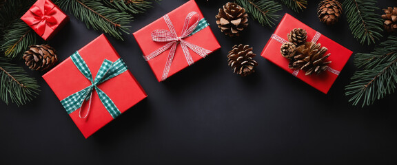 Fototapeta premium Top view of Christmas red gift boxes, fir tree branches and pine cones, Christmas black background 