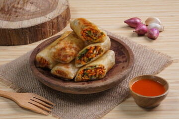 Lumpia or Lunpia, is a traditional snack from central java Indonesia consists of bamboo shoots eggs and meat or shrimp, photographed with wood theme props, studio lighting