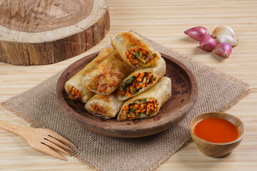 Lumpia or Lunpia, is a traditional snack from central java Indonesia consists of bamboo shoots eggs and meat or shrimp, photographed with wood theme props, studio lighting