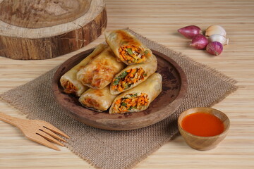 Lumpia or Lunpia, is a traditional snack from central java Indonesia consists of bamboo shoots eggs and meat or shrimp, photographed with wood theme props, studio lighting