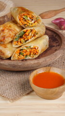 Lumpia or Lunpia, is a traditional snack from central java Indonesia consists of bamboo shoots eggs and meat or shrimp, photographed with wood theme props, studio lighting
