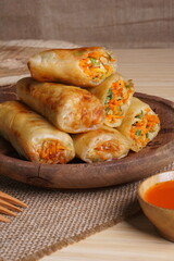 Lumpia or Lunpia, is a traditional snack from central java Indonesia consists of bamboo shoots eggs and meat or shrimp, photographed with wood theme props, studio lighting