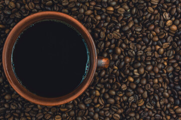Top view of coffee cup surrounded by roasted coffee beans