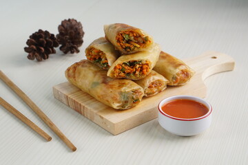 Lumpia or Lunpia, is a traditional snack from central java Indonesia consists of bamboo shoots eggs and meat or shrimp, photographed with wood theme props, studio lighting