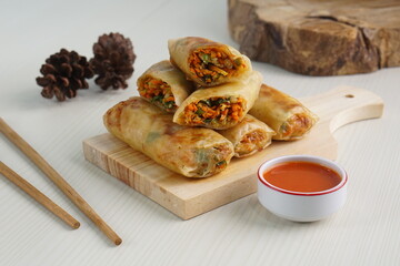Lumpia or Lunpia, is a traditional snack from central java Indonesia consists of bamboo shoots eggs and meat or shrimp, photographed with wood theme props, studio lighting
