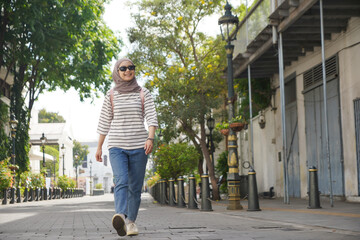 asian muslim woman wearing black sunglasses walking on the street