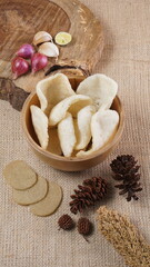 Traditional Indonesian kerupuk snacks, made from catfish, served in a wooden place on a white table with a studio lighting