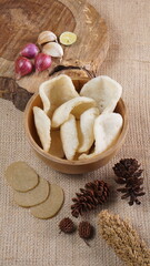 Traditional Indonesian kerupuk snacks, made from catfish, served in a wooden place on a white table with a studio lighting