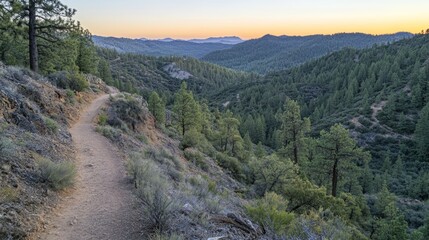 Mountain trail winding through a scenic valley at sunset.