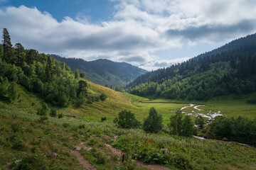 The valley of the Malaya Dukka River surrounded by the mountains of the North Caucasus and the tourist trail to the Dukka Lakes on a sunny summer day, Arkhyz, Karachay-Cherkessia, Russia