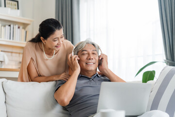 Senior spouses using laptop together sitting on couch at home. Elderly couple, hug and love on sofa with happy marriage, support and conversation of retirement home