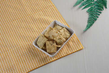 wonton chips on a small white plate on a white table with studio lighting