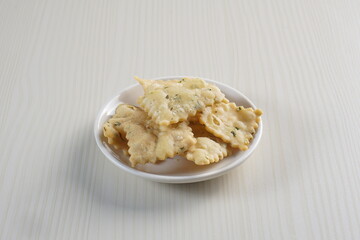 wonton chips on a small white plate on a white table with studio lighting
