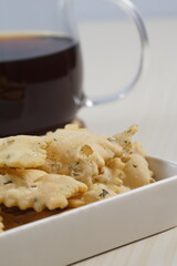 wonton chips in a small white ceramic container on a white table, served with black coffee, with studio lighting