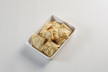 wonton chips on a small white plate on a white table with studio lighting