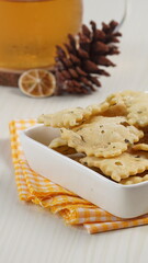 wonton chips in a small white ceramic container on a white table, served with iced tea, with studio lighting