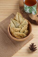 Crispy and savory spinach chips. Made from spinach leaves and rice flour, in a wooden bowl, with wood properties, and studio lighting