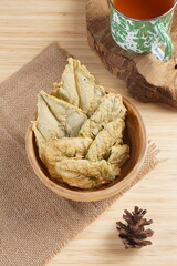 Crispy and savory spinach chips. Made from spinach leaves and rice flour, in a wooden bowl, with wood properties, and studio lighting