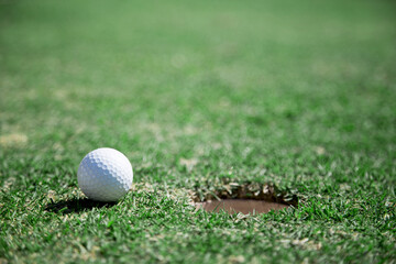 A golf ball about to drop into the hole on a lush green golf course, symbolizing success and achieving a goal