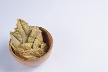 Crispy and savory spinach chips. Made from spinach leaves and rice flour, in a wooden bowl, with a white background and studio lighting