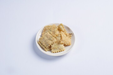 wonton chips on a small white plate on a white table with studio lighting