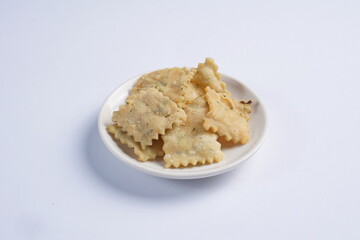 wonton chips on a small white plate on a white table with studio lighting