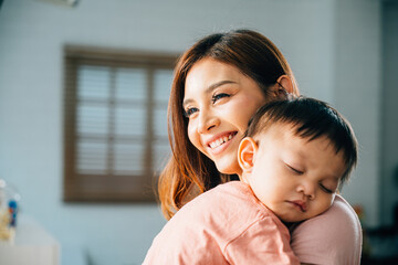 A loving biracial mother tenderly cradles her tiny slumbering newborn sharing a special family moment filled with happiness and affection. The innocence of childhood is beautifully portrayed.