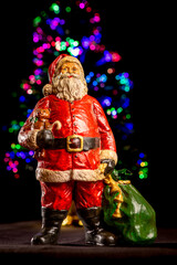 Fototapeta premium This photo features a festive Santa Claus figurine. Santa is depicted wearing his classic red suit with white trim, a black belt with a gold buckle, and black boots. 