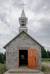 front view of a small wooden church on top of a mountain in summer with the door open