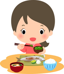 焼き魚などの和食を食べる笑顔の女性