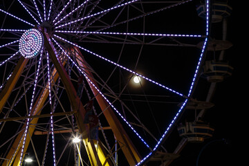 A large, illuminated Ferris wheel with a full moon in the background