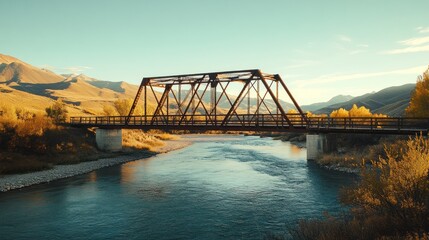 Obraz premium A classic iron truss bridge over a flowing river, set against a backdrop of mountains, late afternoon sun casting shadows, peaceful and natural scenery, ideal for corporate or tourism stock