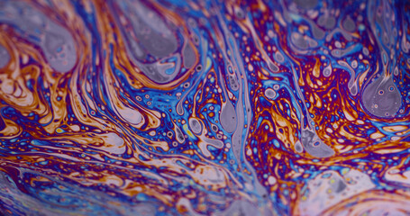Vivid rainbow color. Swirls soap bubble. Defocused purple green liquid oil paint curve acrylic slick on dark black blurred light abstract background.