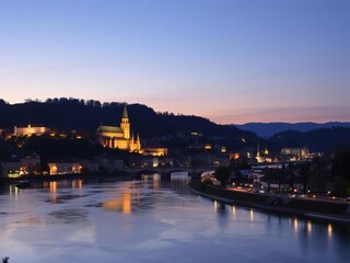 Fototapeta premium City of Salzburg at dusk, river Salzach reflecting lights, historic buildings, illuminated skyline, Austrian cityscape, vibrant colors, twilight scene, skyline, dusk